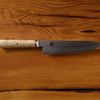 Damascus steel chef knife with cork handle on wooden background.