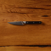 Chef's knife with black handle on wooden table.