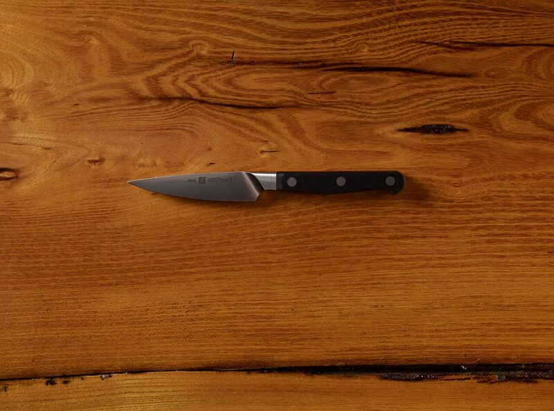 Chef's knife with black handle on wooden table.