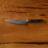Chef's knife with black handle on wooden background