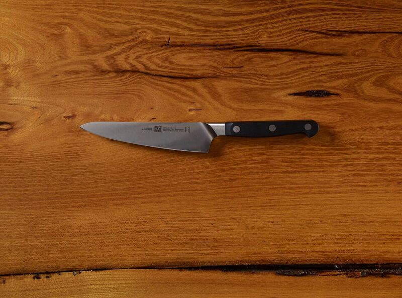 Chef's knife with black handle on wooden background