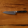 Stainless steel chef's knife with black handle on wooden surface