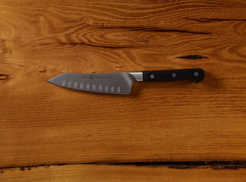 Stainless steel chef's knife with black handle on wooden surface