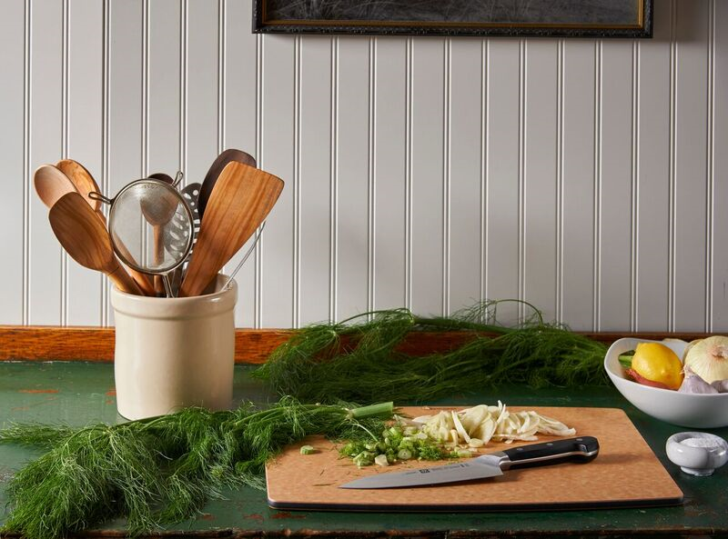 Kitchen counter with utensils, chopped vegetables, and a bowl of lemons.