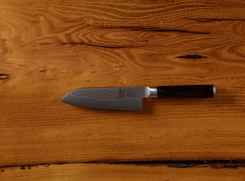 Chef's knife with damascus blade pattern on wooden surface