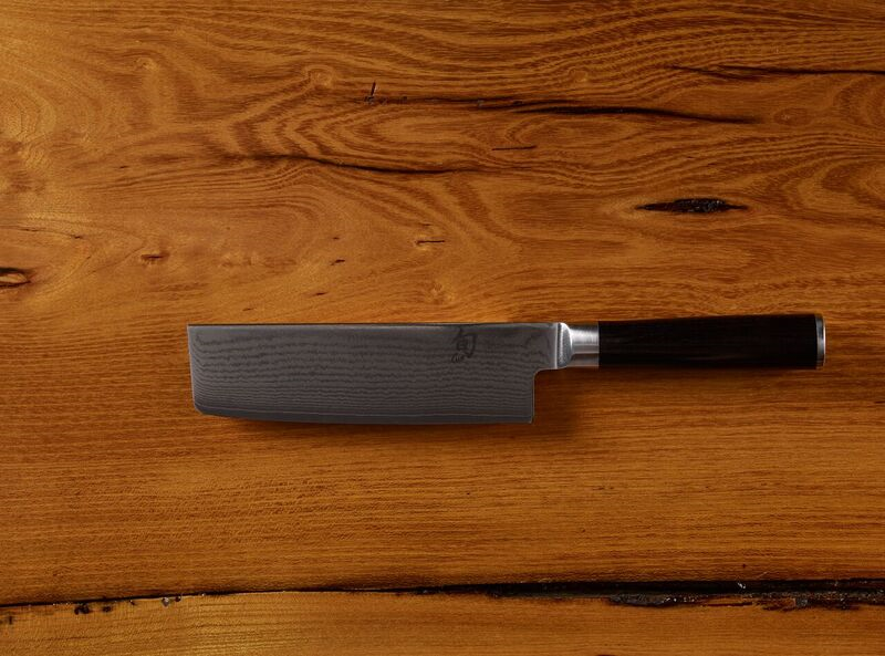 Japanese chef knife with black handle on wooden surface
