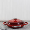 Red Le Creuset cast iron casserole dish on marble countertop