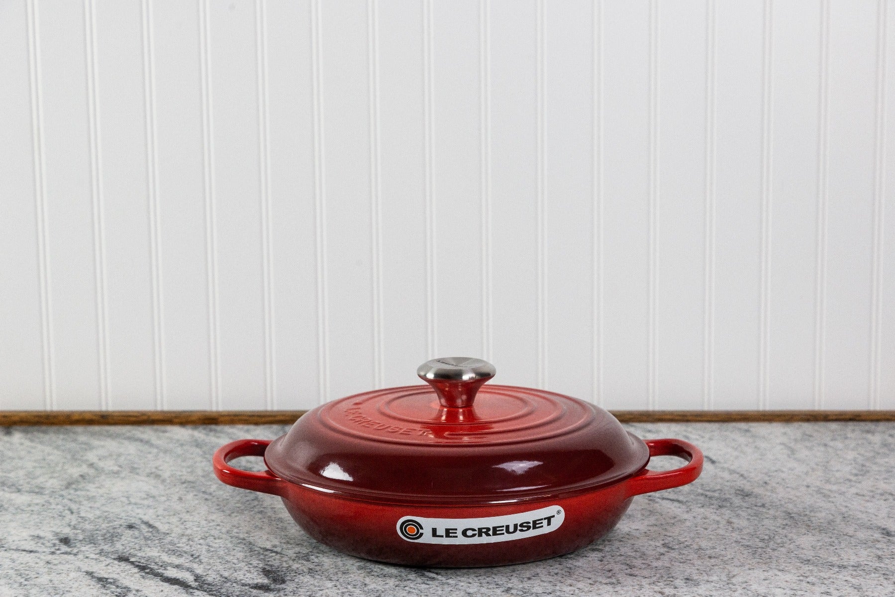 Red Le Creuset cast iron casserole dish on marble countertop