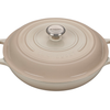 Beige Le Creuset cast iron dutch oven with lid on white background