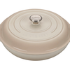 Beige enameled cast iron Dutch oven by Le Creuset on white background