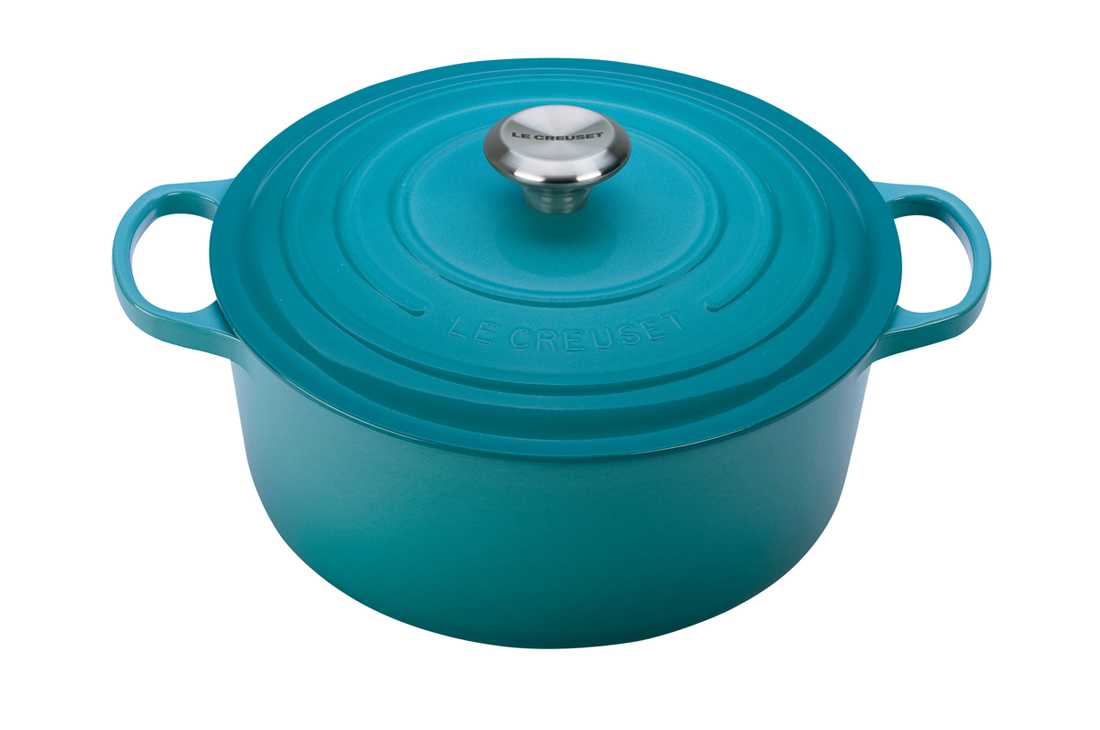 Teal enameled cast iron Le Creuset dutch oven with lid on white