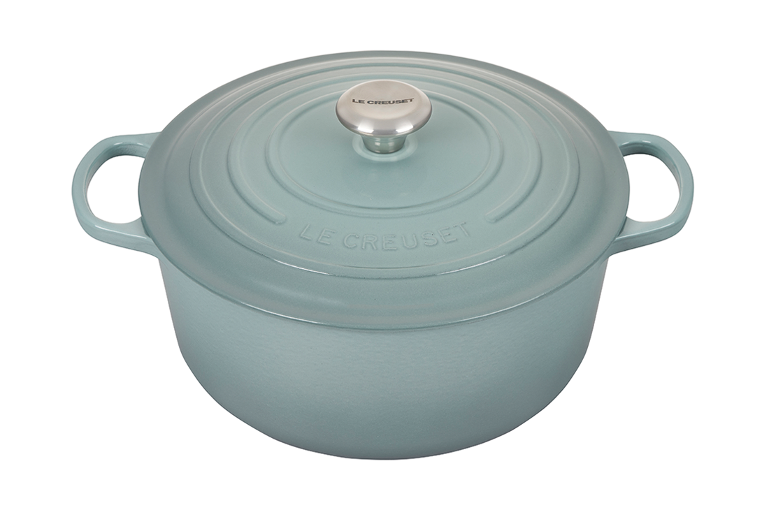 Light blue Le Creuset cast iron dutch oven on white background.