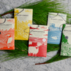 Five assorted LeRoux chocolate bars on marble with pine needles decoration.