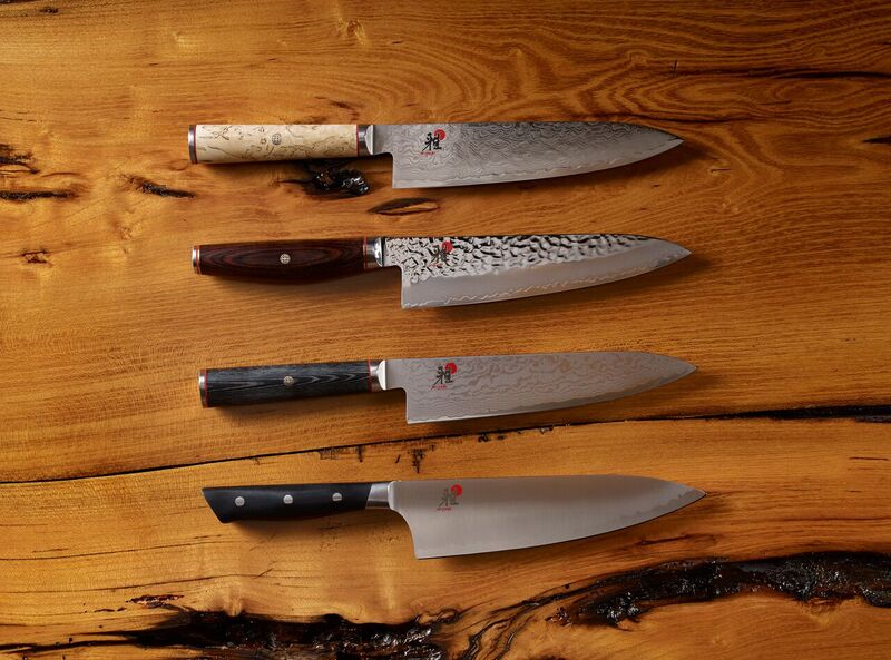Five chef knives with unique handles displayed on a wooden surface