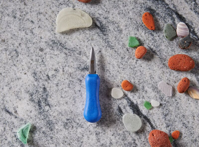 Blue screwdriver on marble surface with colorful sea glass and pebbles