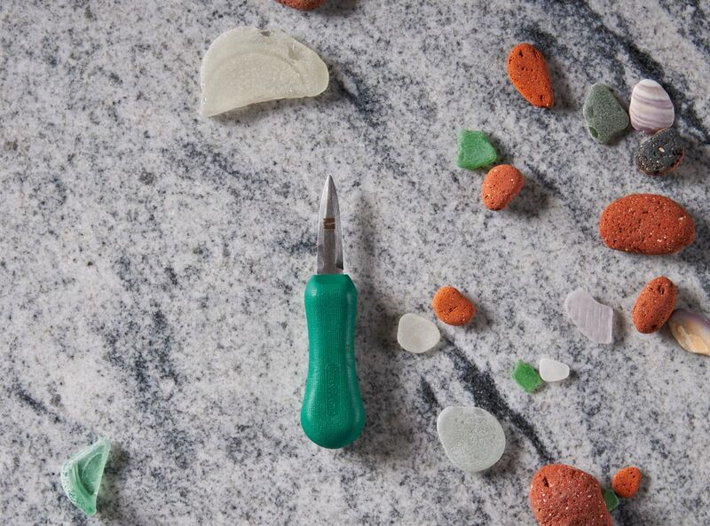 Green screwdriver and colorful sea glass pieces on granite surface