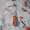 Pocket knife with wooden handle amid colorful sea glass pieces on marble surface.