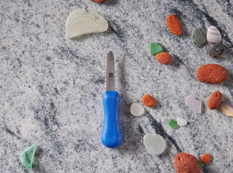Blue screwdriver on marble surface with colorful sea pebbles around it