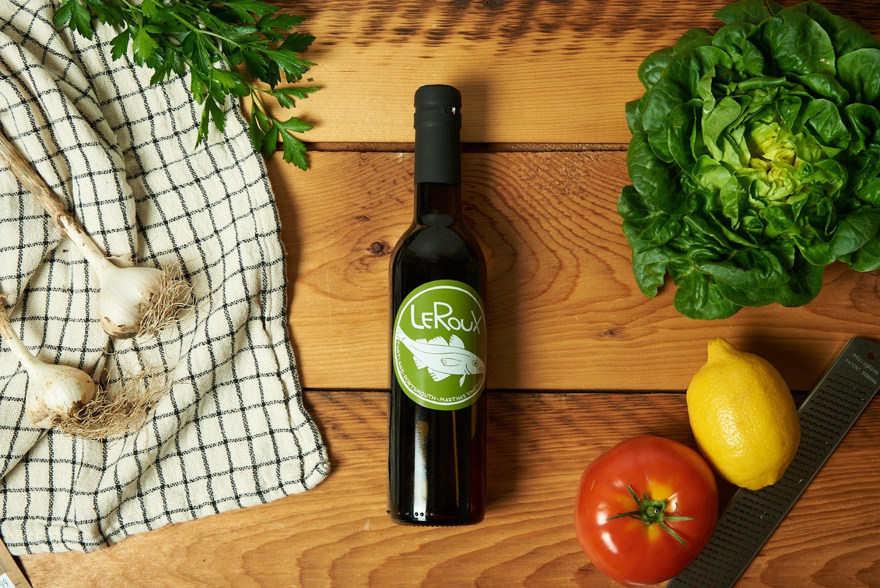 Bottle of LeRoux vermouth with fresh produce on wooden table