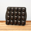 Vintage face-shaped chocolate mold on wooden surface against white wall