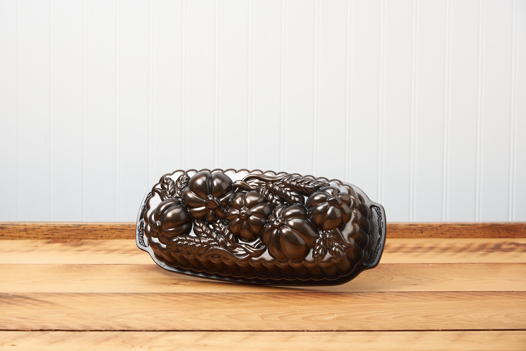 Vintage floral patterned cast iron loaf pan on a wooden table.