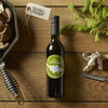 Variety of fresh mushrooms in a pan with olive oil bottle and herbs on wooden surface.