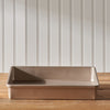 A 9"x13" OXO Cake Pan sits on a wooden table, in front of a white wall.