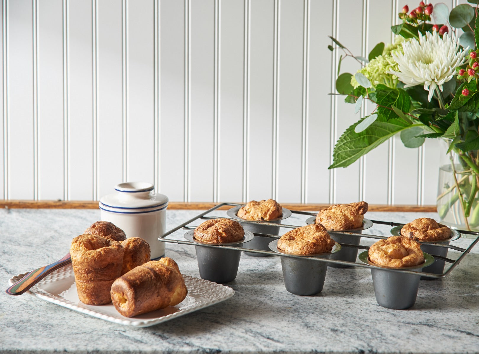 Freshly baked popovers on cooling rack with sugar container and flowers