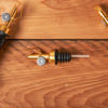 Elegant golden wine pourers on wooden table, wine tasting accessory