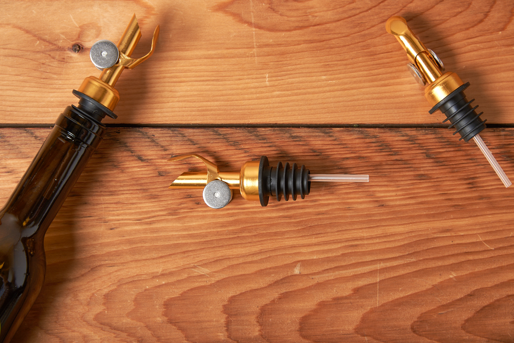Elegant golden wine pourers on wooden table, wine tasting accessory