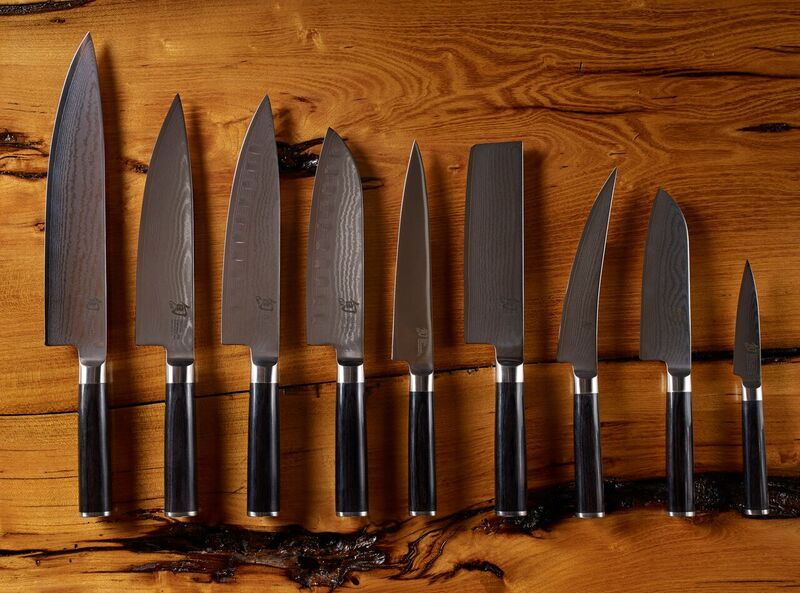 Assorted Japanese kitchen knives arranged in a row on a wooden surface