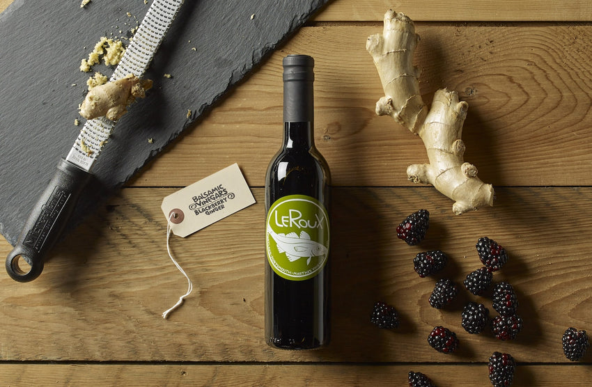 Wine bottle with ginger and blackberries on a wooden table