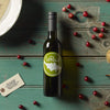 Bottle of LeRoux wine with pears and cranberries on wooden table.