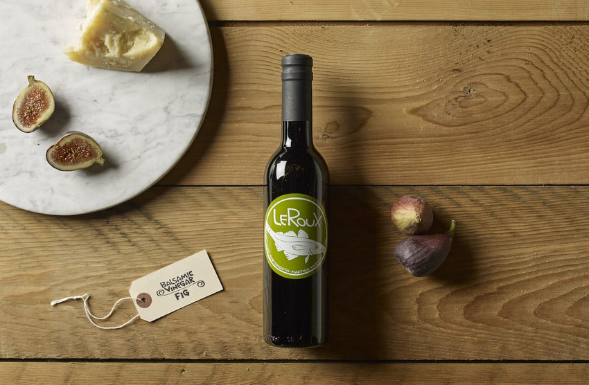 Fig balsamic vinegar bottle on wood with cheese and figs